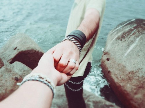 couple-holding-hands-near-rocks-by-sea