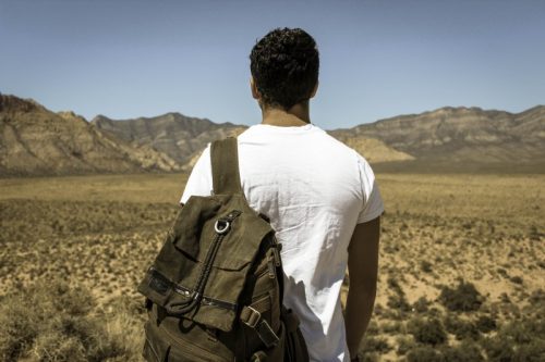 backpacker-standing-on-desert-and-looking-at-mountains